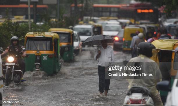 Commuters wade through a water-logged road due to heavy rainfall, at Ranjit Flyover, on July 13, 2018 in New Delhi, India. The heavy rains came as a...