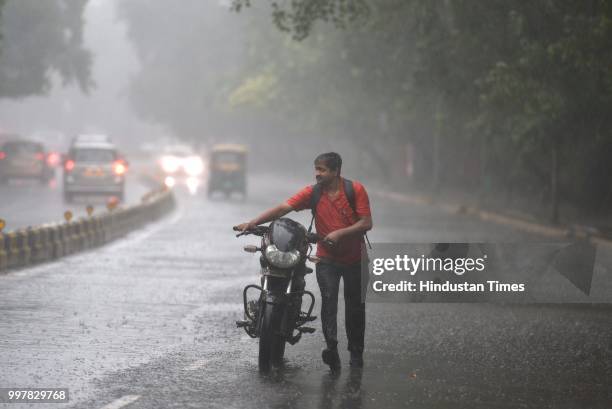 Man seen with his motorcycle during heavy rainfall at Tolstoy Marg, on July 13, 2018 in New Delhi, India. The heavy rains came as a respite to the...