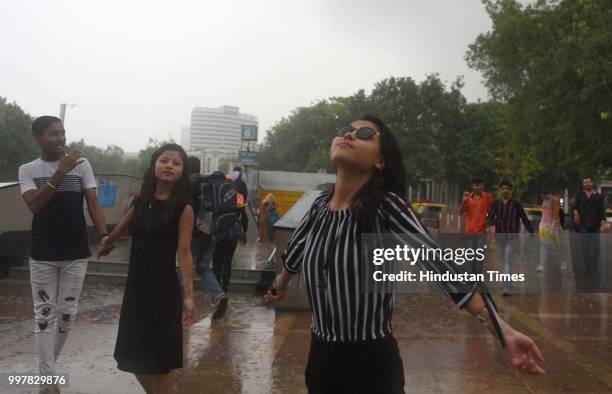 People seen enjoying the showers as rain hits the city, at Connaught Place, on July 13, 2018 in New Delhi, India. The heavy rains came as a respite...