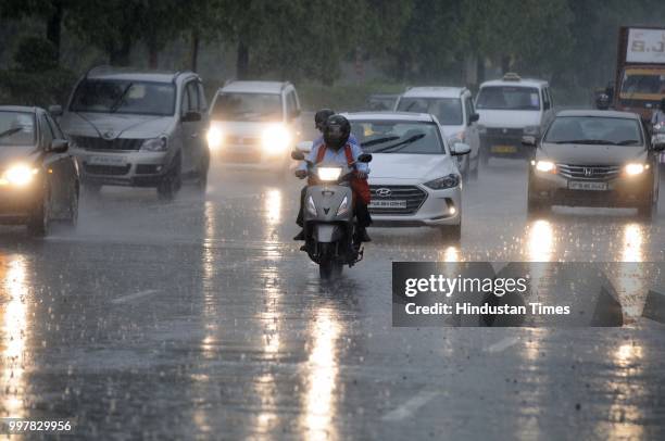 Commuters travel during heavy rainfall near Film City road, on July 13, 2018 in Noida, India. The heavy rains came as a respite to the people of...