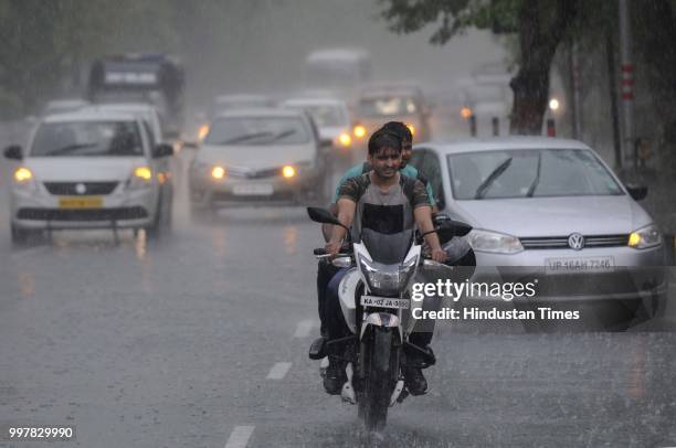 Commuters travel during heavy rainfall near Film City road, on July 13, 2018 in Noida, India. The heavy rains came as a respite to the people of...