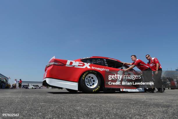 Crew members push the car of Ryan Blaney, driver of the DEX Imaging Ford, through the garage area during practice for the Monster Energy NASCAR Cup...