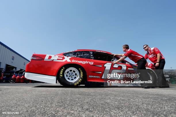 Crew members push the car of Ryan Blaney, driver of the DEX Imaging Ford, through the garage area during practice for the Monster Energy NASCAR Cup...