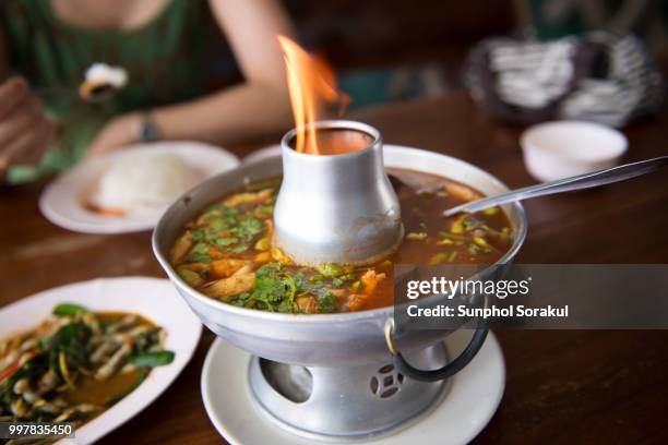 thai spicy orange curry served in a flamed steamboat pot - sunphol foto e immagini stock