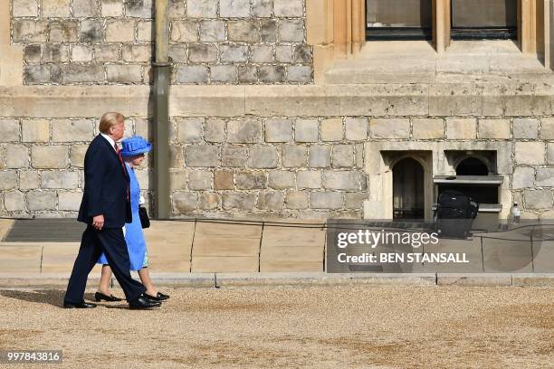 Britain's Queen Elizabeth II walks with US President Donald Trump in the Quadrangle at Windsor Castle in Windsor, west of London, on July 13, 2018...