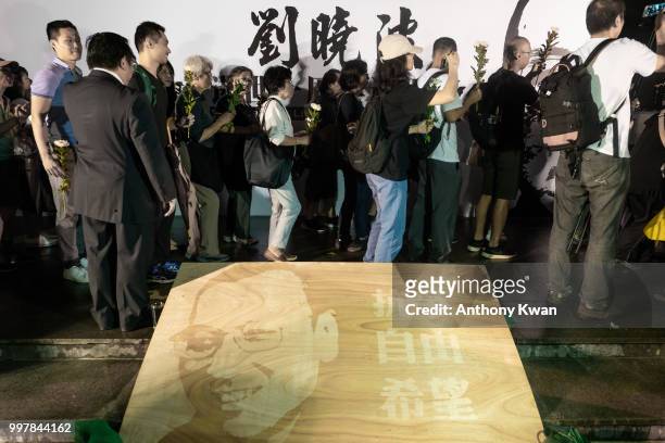Vigil participants wait in line to lay flowers in front of statue of Liu Xiaobo during a memorial vigil held for Chinese Nobel Peace Prize-winner Liu...