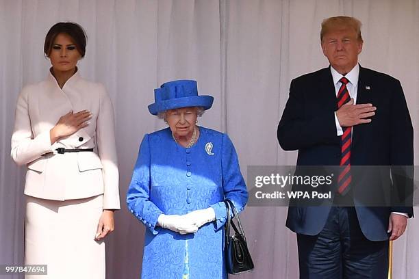 Britain's Queen Elizabeth II stands with US President Donald Trump and US First Lady Melania Trump on the dias in the Quadrangle listening to a band...