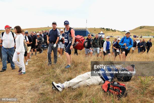Spectator sleeps in the grass as Padraig Harrington of Ireland plays his second shot on hole eighteen during day two of the Aberdeen Standard...