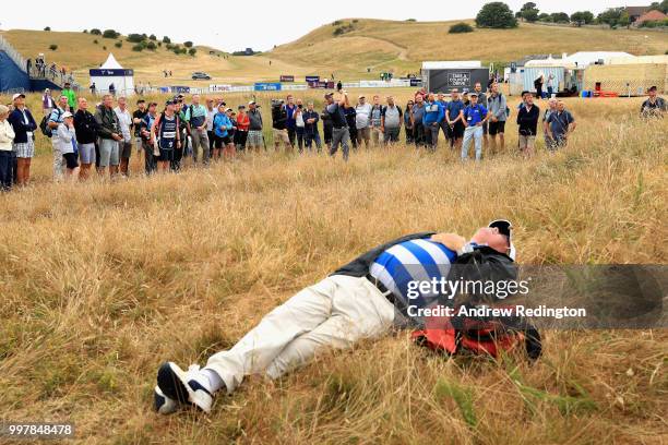 Spectator sleeps in the grass as Padraig Harrington of Ireland plays his second shot on hole eighteen during day two of the Aberdeen Standard...