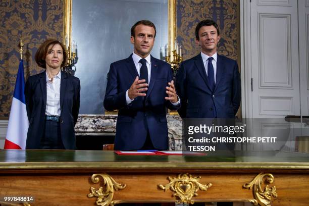 French President Emmanuel Macron , flanked by French Defense Minister Florence Parly and French government spokesman Benjamin Griveaux , addresses...