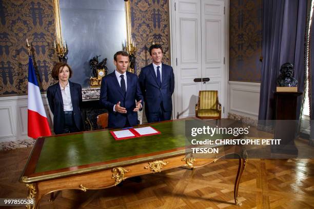 French President Emmanuel Macron , flanked by French Defense Minister Florence Parly and French government spokesman Benjamin Griveaux , after...