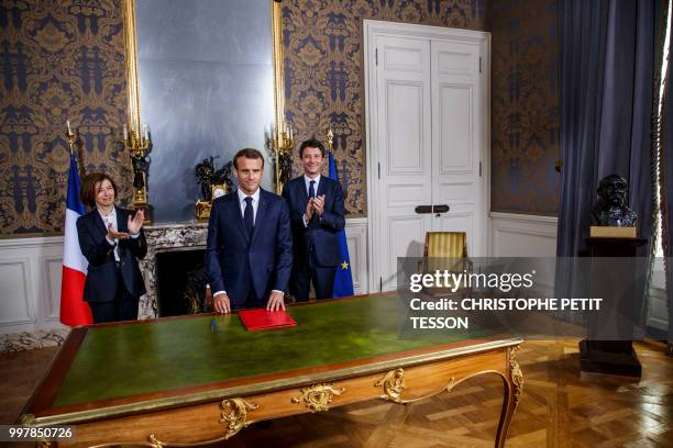 French President Emmanuel Macron , flanked by French Defense Minister Florence Parly and French government spokesman Benjamin Griveaux , signs the...