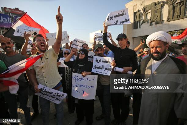 Iraqis shout slogans and raise national flags during a protest against poor services, unemployment and corruption as they gather in the capital...