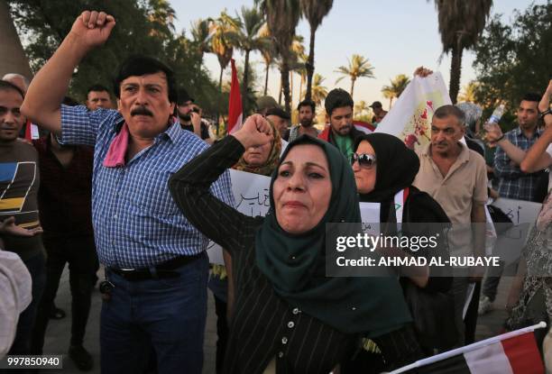 Iraqis shout slogans and raise national flags during a protest against poor services, unemployment and corruption as they gather in the capital...