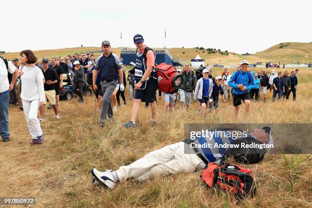 Spectator sleeps in the grass as Padraig Harrington of Ireland plays his second shot on hole eighteen during day two of the Aberdeen Standard...