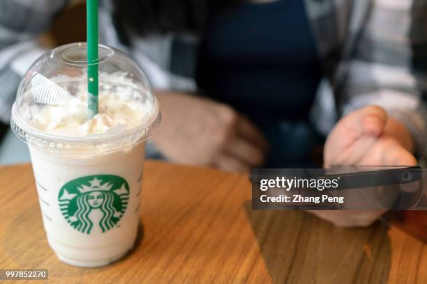 Girl drinks a Starbucks coffee with a plastic straw. Starbucks announced on July 9th that it would ban the use of plastic straws in its 28 thousand...