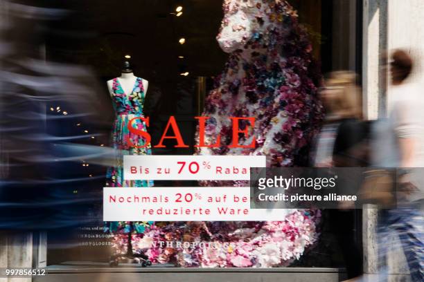 July 2018, Duesseldorf, Germany: Two women walk by a store which is promoting its wares with a summer sale. The summer sale has started in...