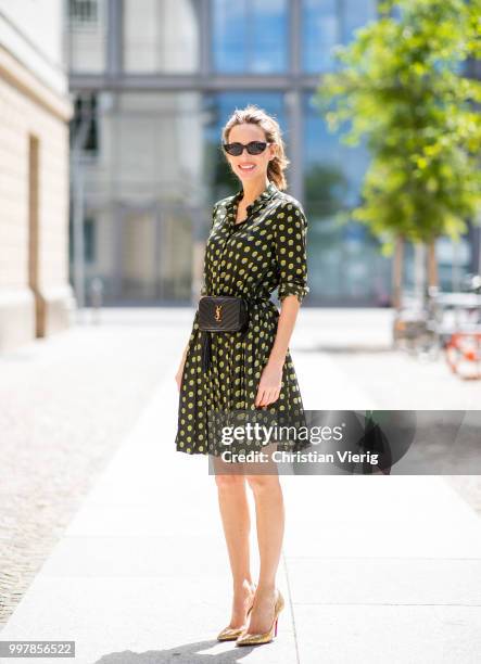 Alexandra Lapp is seen wearing a knee length dark green dress with green and yellow dots from Steffen Schraut, the Lou Belt Bag in black by Saint...