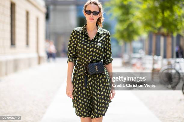 Alexandra Lapp is seen wearing a knee length dark green dress with green and yellow dots from Steffen Schraut, the Lou Belt Bag in black by Saint...