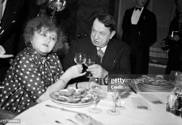 French writer, poet and journalist Francis Carco toasts with French writer Colette for Robert Merle's victory at the Prix Goncourt award, on December...