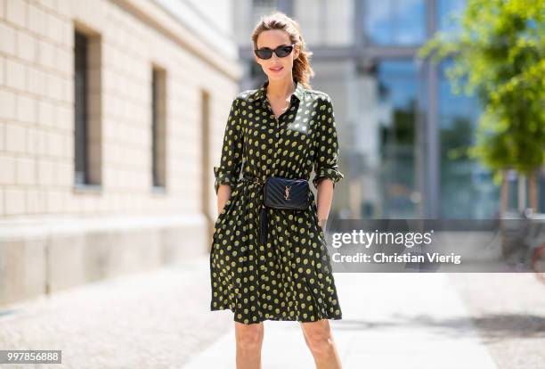 Alexandra Lapp is seen wearing a knee length dark green dress with green and yellow dots from Steffen Schraut, the Lou Belt Bag in black by Saint...