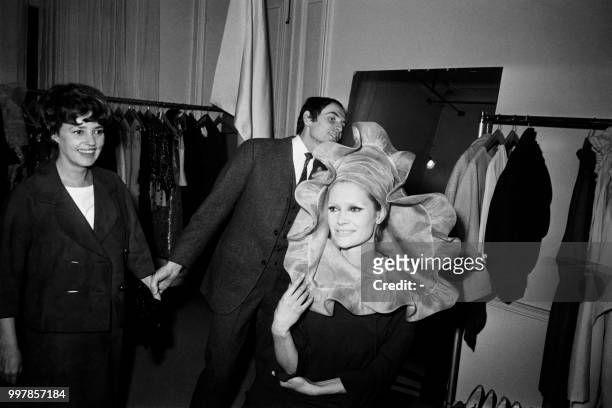French fashion-designer Pierre Cardin retouches Annabelle's hat as French actress Jeanne Moreau looks on, on January 29, 1963.