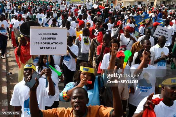 Demontrator holds a placard reading 'A thirsty Senegal, starving people' as Senegalese opponents protest against the electoral system on July 13,...