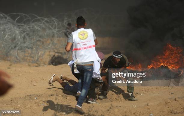 Medics carry a wounded Palestinian as Israeli forces intervene to disperse Palestinian demonstrators taking part in the "Great March of Return"...