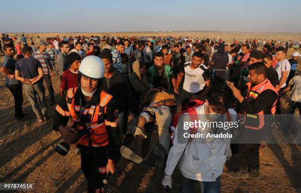 Medics carry a wounded Palestinian as Israeli forces intervene to disperse Palestinian demonstrators taking part in the "Great March of Return"...