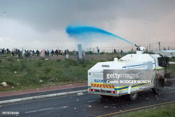 South African Police water cannon fires water to disperse protesters during clashes with police calling for the release of one of their colleagues,...