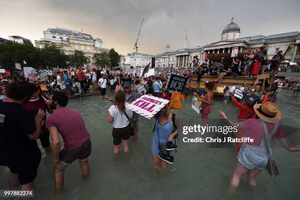 Woman holds a placard as she wades in one of the fountains after a demonstration against President Trump's visit to the UK in Trafalgar Square on...