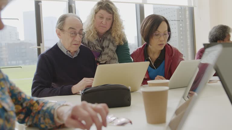 Computer Networking Instructor Instructor helping senior students using laptops in computer training ...
