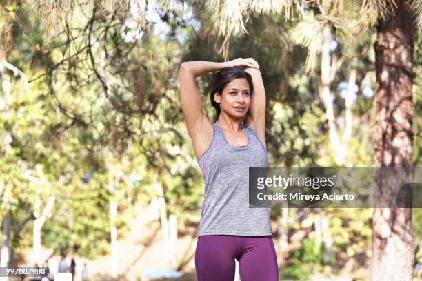 fit, ethnic woman stretches before a work out in a park in work out clothes. - mireya acierto stockfoto's en -beelden