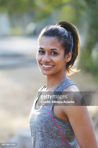 fit, ethnic woman poses for camera in los angeles park in work out clothes - mireya acierto stockfoto's en -beelden