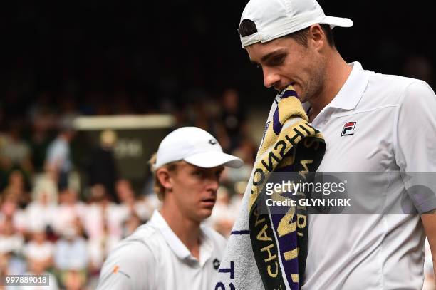 Player John Isner returns passes South Africa's Kevin Anderson as they change ends of the court in the final set tie-break of their men's singles...
