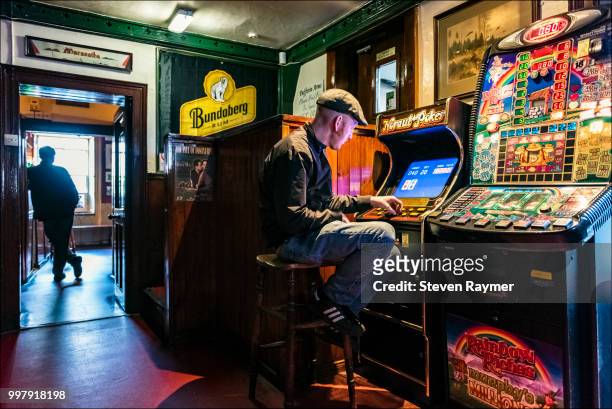 man plays game machine in northern ireland pub - solitaire fotografías e imágenes de stock