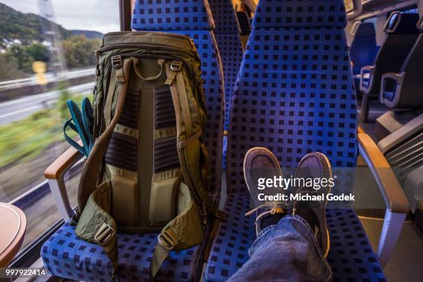 backpacker's feet resting on seat in train - asiento fotografías e imágenes de stock