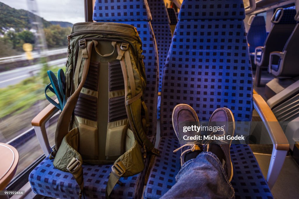 Backpacker's feet resting on seat in train