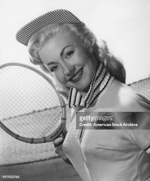 Portrait of an unidentified model, in a tennis outfit and matching hat, as she poses with tennis racket, Los Angeles, California, January 25, 1958.