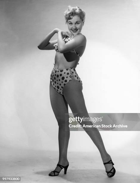 Portrait of an unidentified model, in a two-piece, polka-dot bathing suit and high heels, as she poses in a studio, Los Angeles, California, January...