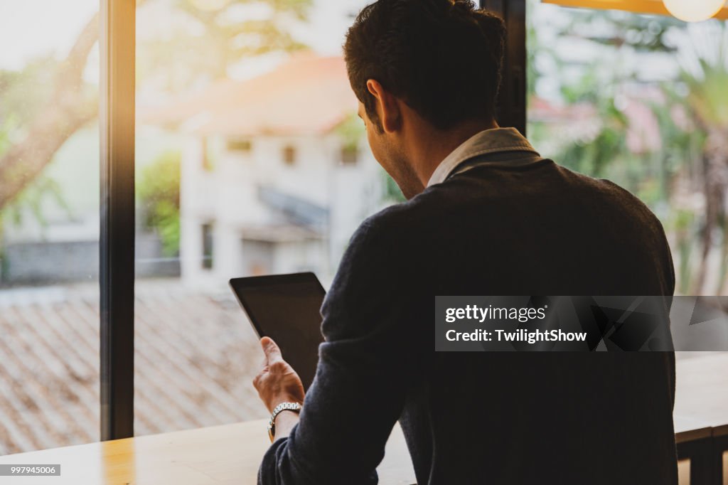 One young adult male sat using his tablet in office