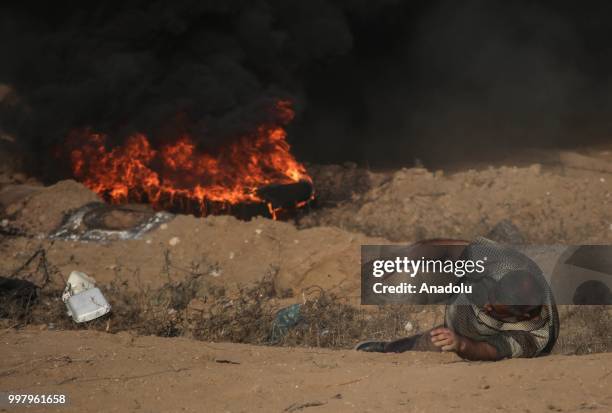 Palestinian man lies on the ground after Israeli security forces fired tear gas during the "Great March of Return" demonstration with ''Fidelity to...