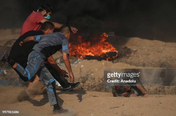 Palestinian man lies on the ground after Israeli security forces fired tear gas during the "Great March of Return" demonstration with ''Fidelity to...