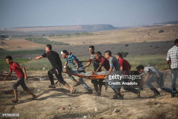 Medics carry a wounded Palestinian after Israeli security forces' intervention during the "Great March of Return" demonstration with ''Fidelity to...