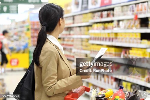 Woman holding smart phone with shopping list in supermarket Woman holding smart phone with shopping list in supermarket