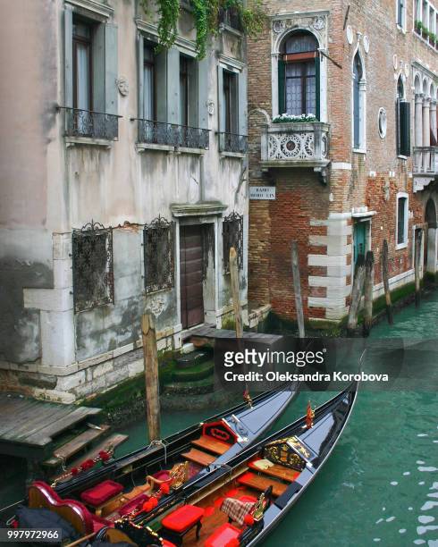 gondolas with ornate gilded details tied up on the banks of the historic canals in venice. - ornate house furniture stock-fotos und bilder