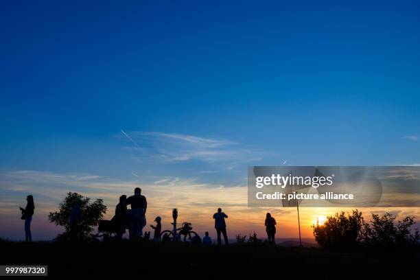 Hikers gather on the summit of a mountain as the sun sets over Bad Staffelstein, Germany, 7 August 2017. Crowds gathered across Germany to witness a...