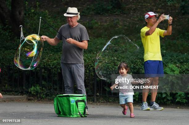 Little girl screams in joy as she pops a big bubble in Central Park on July 13, 2018 in New York.