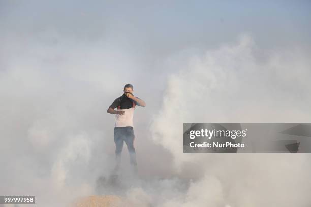 Palestinian man reacts from tear gas fired by Israeli troops during a demonstration along the border with Israel east of Gaza City.July 13, 2018.