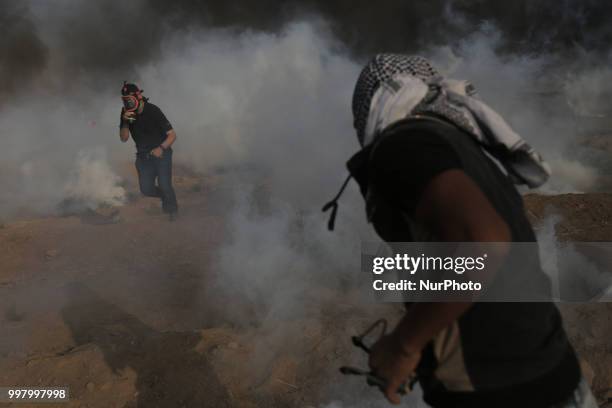 Picture taken on July 13, 2018 shows tear gas canisters fired by Israeli forces landing amidst protesters during a demonstration along the border...